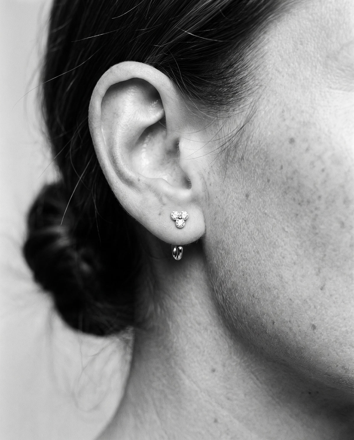 Clear Cluster Open Hoop in Sterling Silver on an earlobe, in black and white.