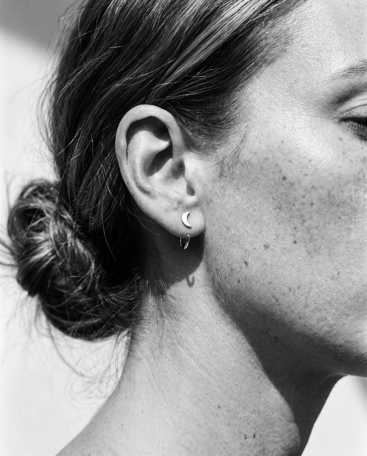 Crescent Open Hoop in Sterling Silver on an ear, in black and white.