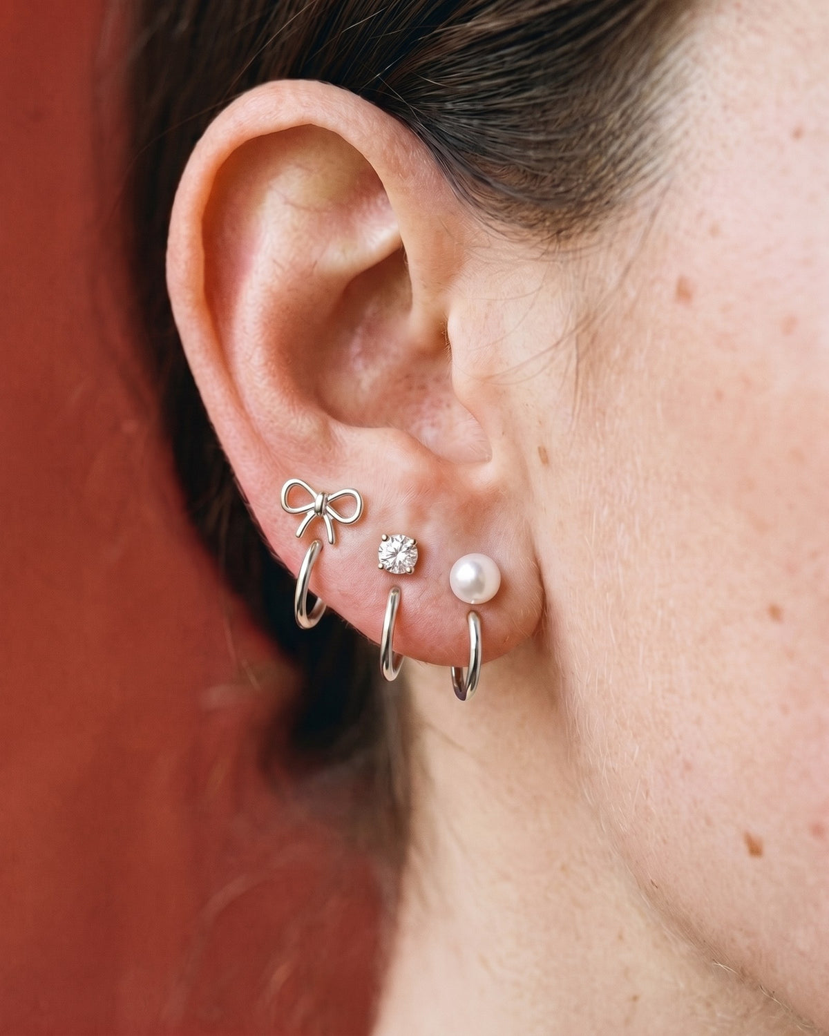 The Bow, Clear Round and White Bead set in Sterling Silver, worn on one ear