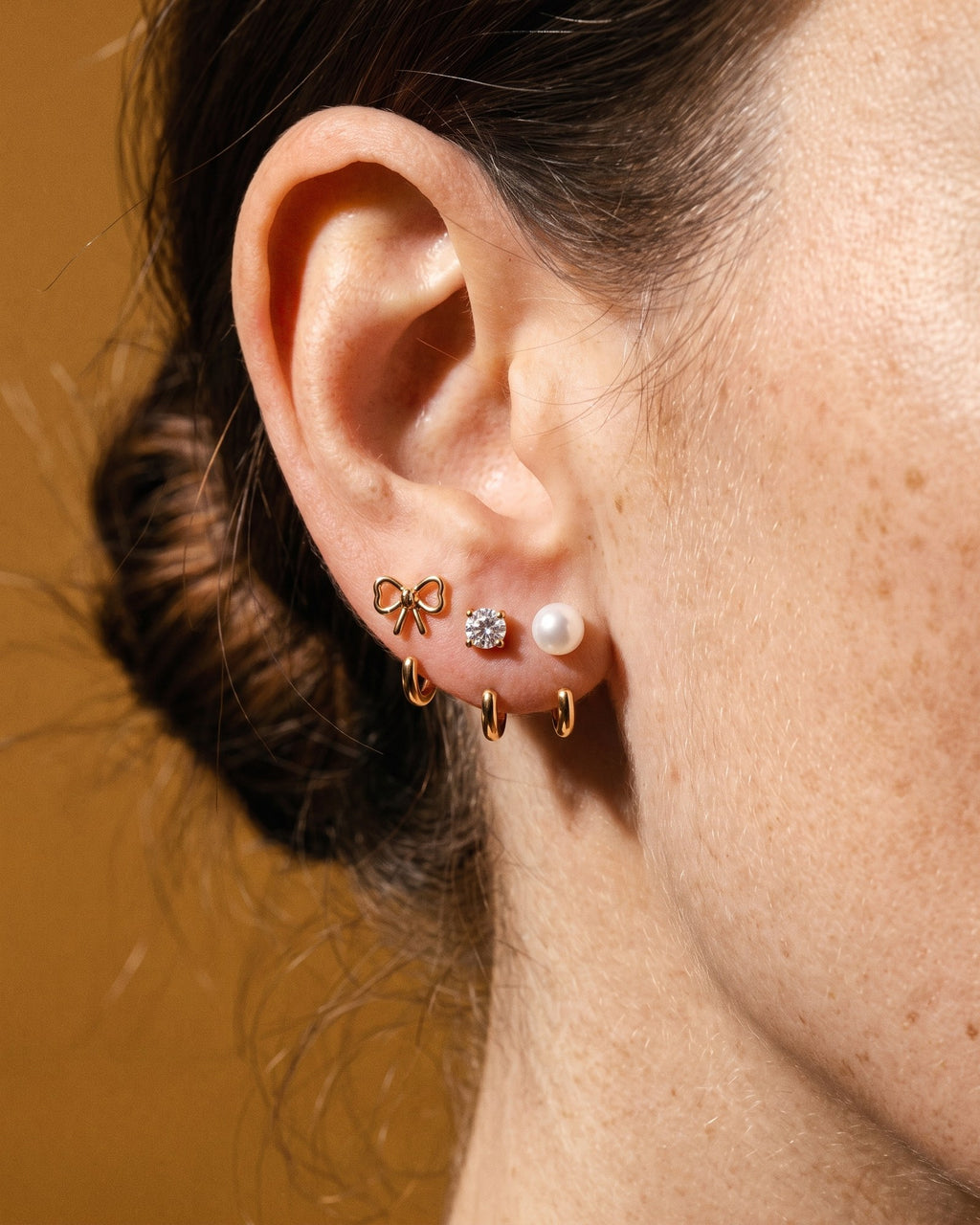The Bow, Clear Round and White Bead set in 18K Gold Vermeil, worn on one ear